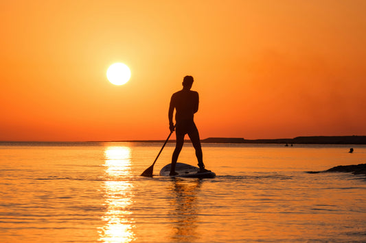 Man paddle boarding at sunset